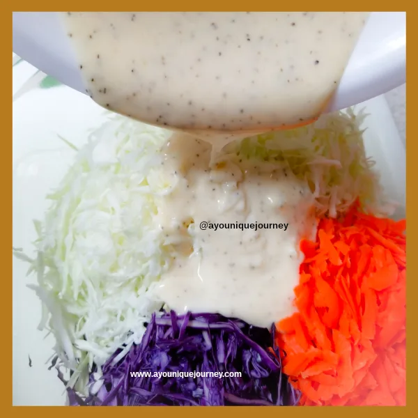 Pouring the Coleslaw Dressing on the shredded vegetables: purple and green cabbage and carrots