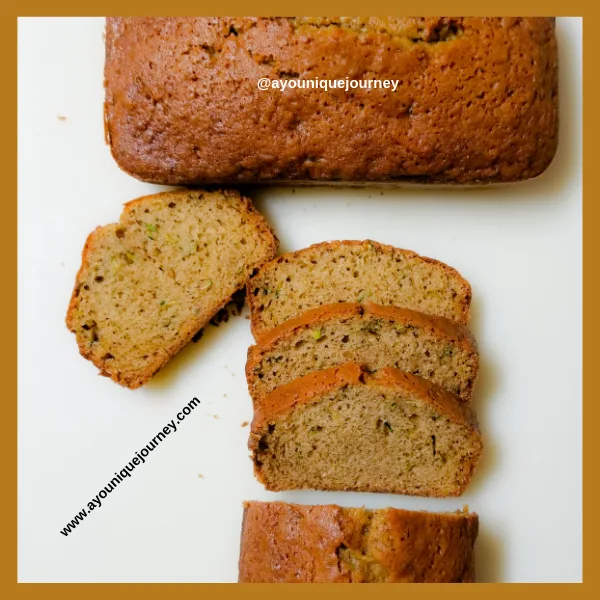 A Zucchini Bread with a few slices on a white cutting board.