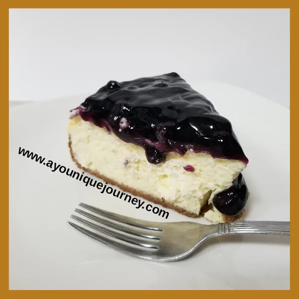 A slice of Blueberry Cheesecake on a white plate.