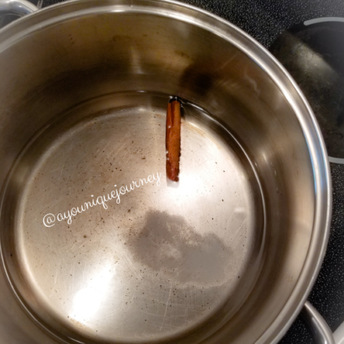 Boiling water, salt with a cinnamon stick to make Jamaican Plantain Porridge.