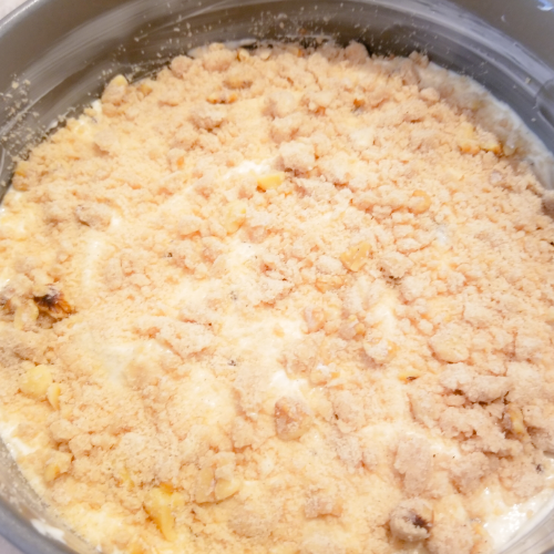 Adding a layer of the crumble mixture over half of the coffee cake batter.