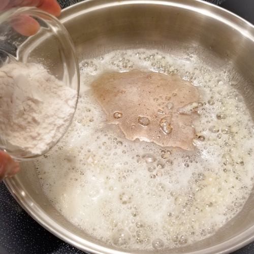 Adding the flour to the heated garlic butter mixture.