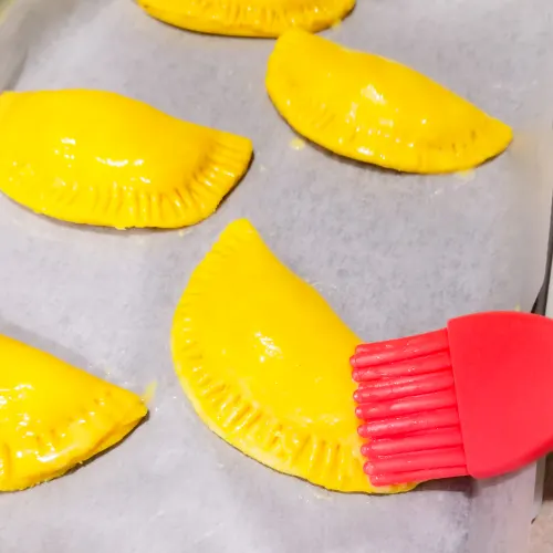 Brushing the Jamaican Beef Patty with the egg wash just before putting them in the oven.