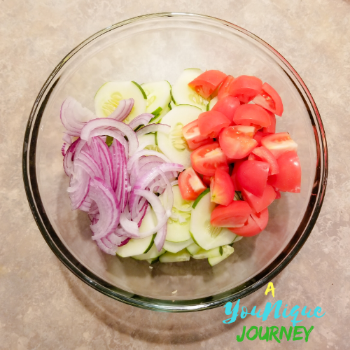 The slices cucumber, tomato and red onion in a large bowl.