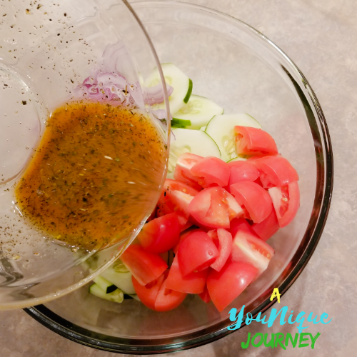 Pouring the dressing over the cucumber tomato and red onions.