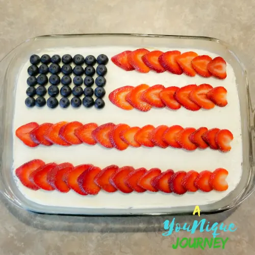 After adding the strawberries on the top of the red white and blue poke cake.