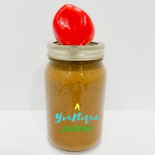 Jerk Marinade Sauce in a Mason Jar with a red scotch bonnnet pepper on top.