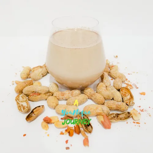 A glass of high energy Peanut Punch with peanuts around it.