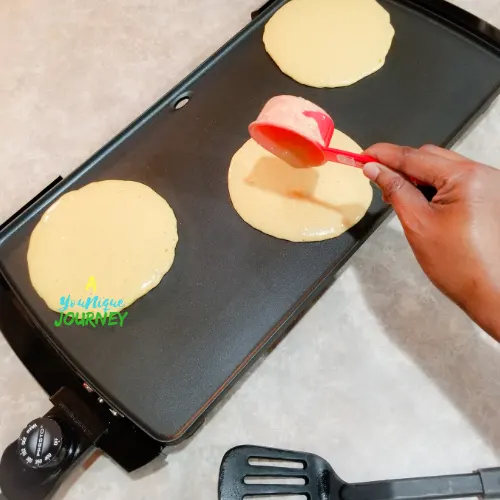 Pouring a 1/3 cup of batter on to the heated griddle.