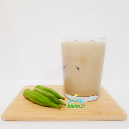 A glass of Okra Punch with okras on a cutting board.