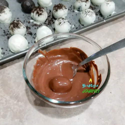 Coating the oreo balls in melted chocolate.