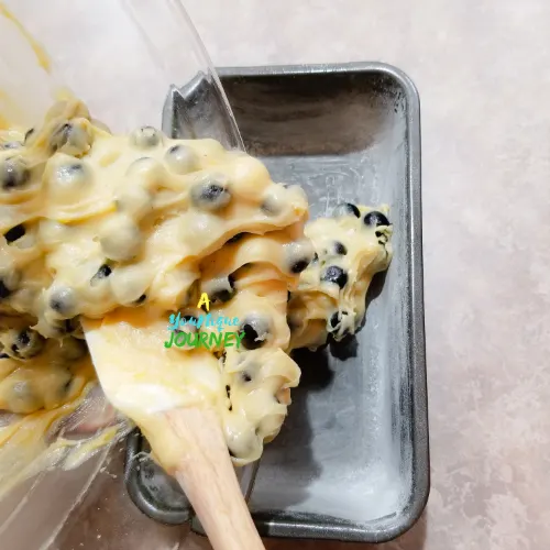 Adding the blueberry batter to the prepared loaf pan.