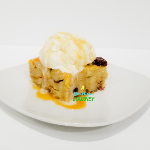 Eggnog Bread Pudding with a scoop of vanilla ice cream on top drizzled with rum sauce.