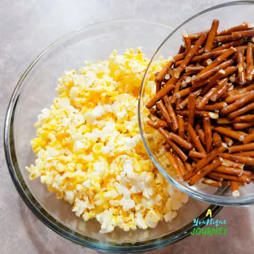 Adding the broken pretzels to the popcorn.