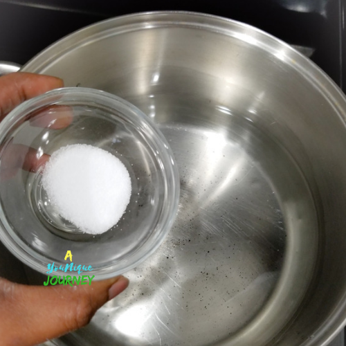 Adding salt to the water in a large pot to cook Jamaican Boiled Dumplings.
