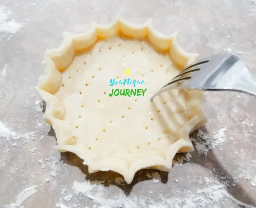 Poking the pastry shell with a fork to prevent the dough from puffy up while baking.