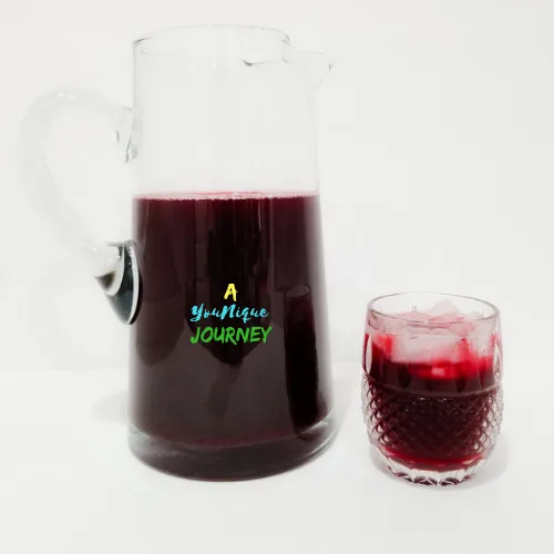 Jamaican Sorrel Drink in a large pitcher and glass with ice.