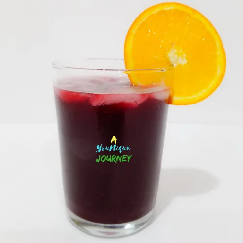 Jamaican Sorrel Drink in a glass with ice and a slice of orange.