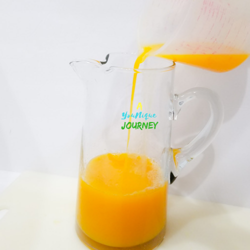Pouring the strained mango puree in the large pitcher.
