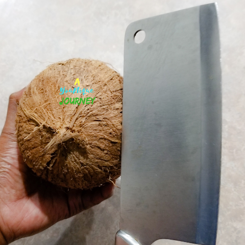 Using a chopper cleaver to break the coconut open to make homemade coconut milk.