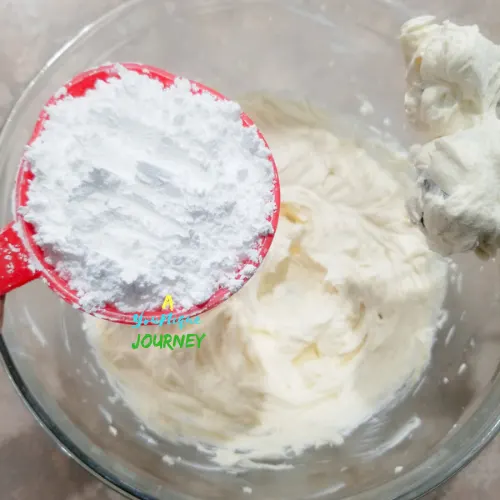 Adding the powdered sugar to the cream cheese mixture.