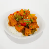 Sweet and sour Chicken served with white rice in a white bowl.