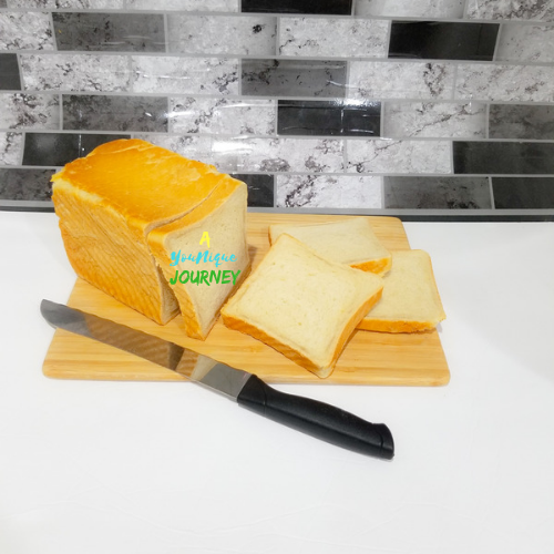 A few slices of Jamaican Hard Dough Bread on a cutting board with a bread knife beside it.