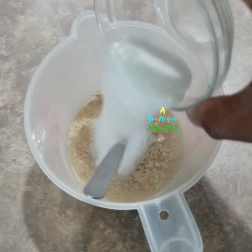 Adding the granulated sugar to the yeast and warm water.
