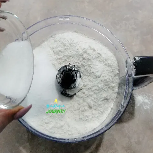 Adding remaining granulated sugar to the flour, salt and nutmeg to make the dough for the Jamaican Hard Dough Bread.