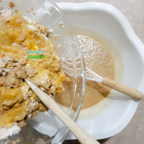 Adding the grated sweet potatoes, yellow yam and coco to the mixture.