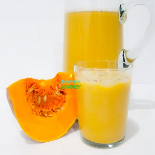 Jamaican Pumpkin Punch in a glass and a pitcher with a piece of pumpkin.