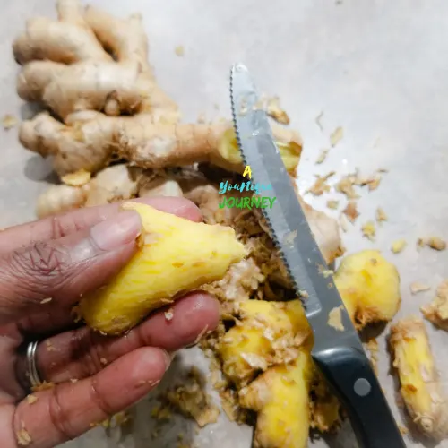 Scraping the skin off the ginger root pieces.