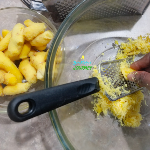 Using a small and box grater to grater the ginger root pieces.