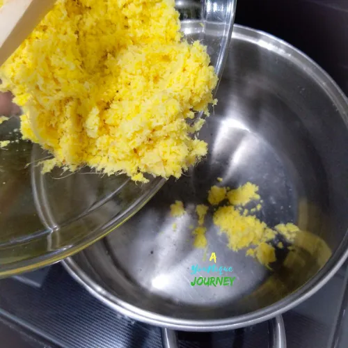 Adding the grated ginger to a large pot to make Homemade Jamaican Ginger Beer.