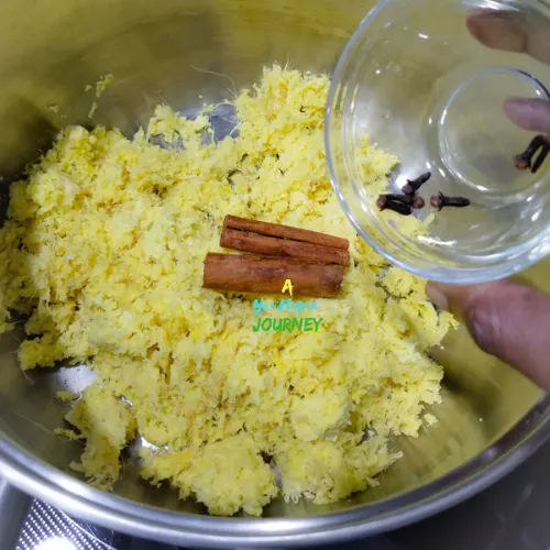 Adding the cloves to the grated ginger and cinnamon sticks.